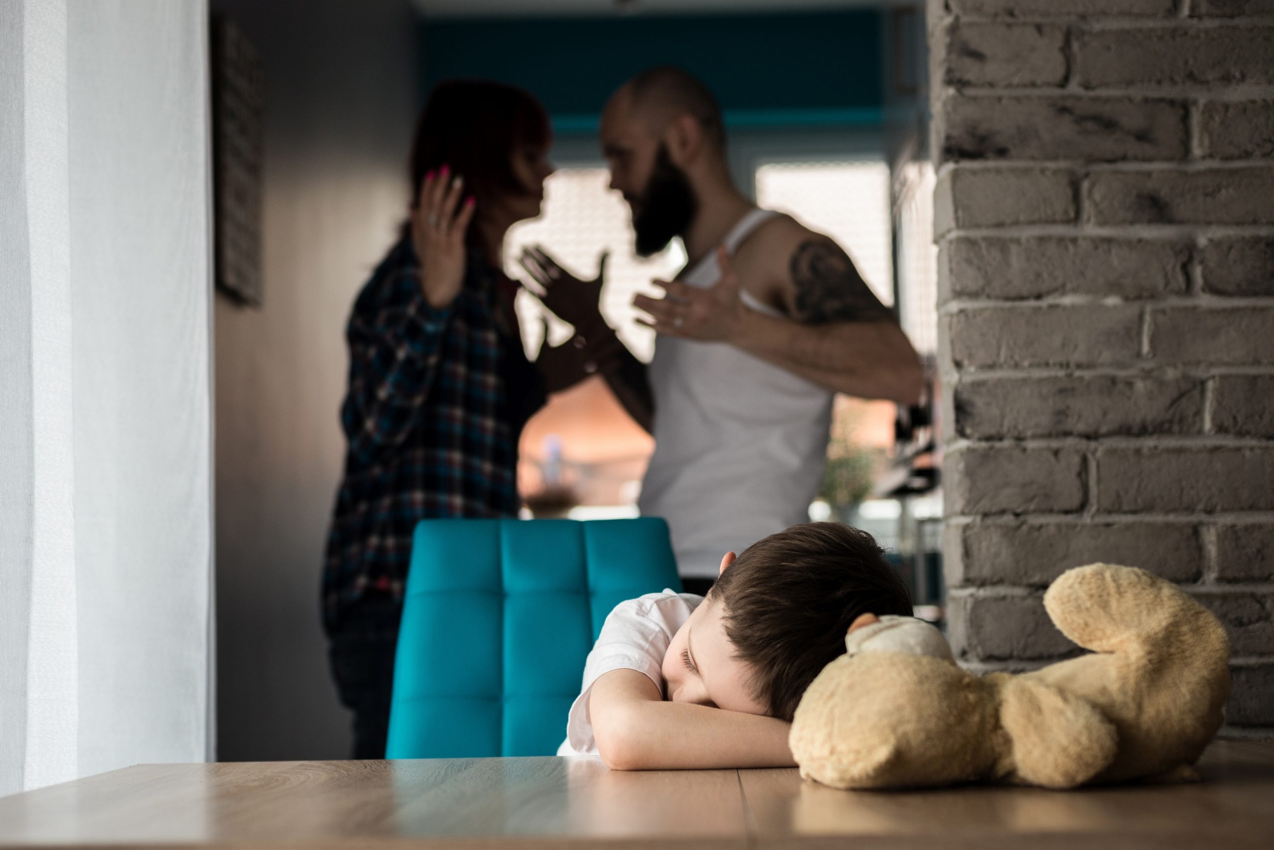 Ruziënd stel en verdrietig kind met teddybeer.