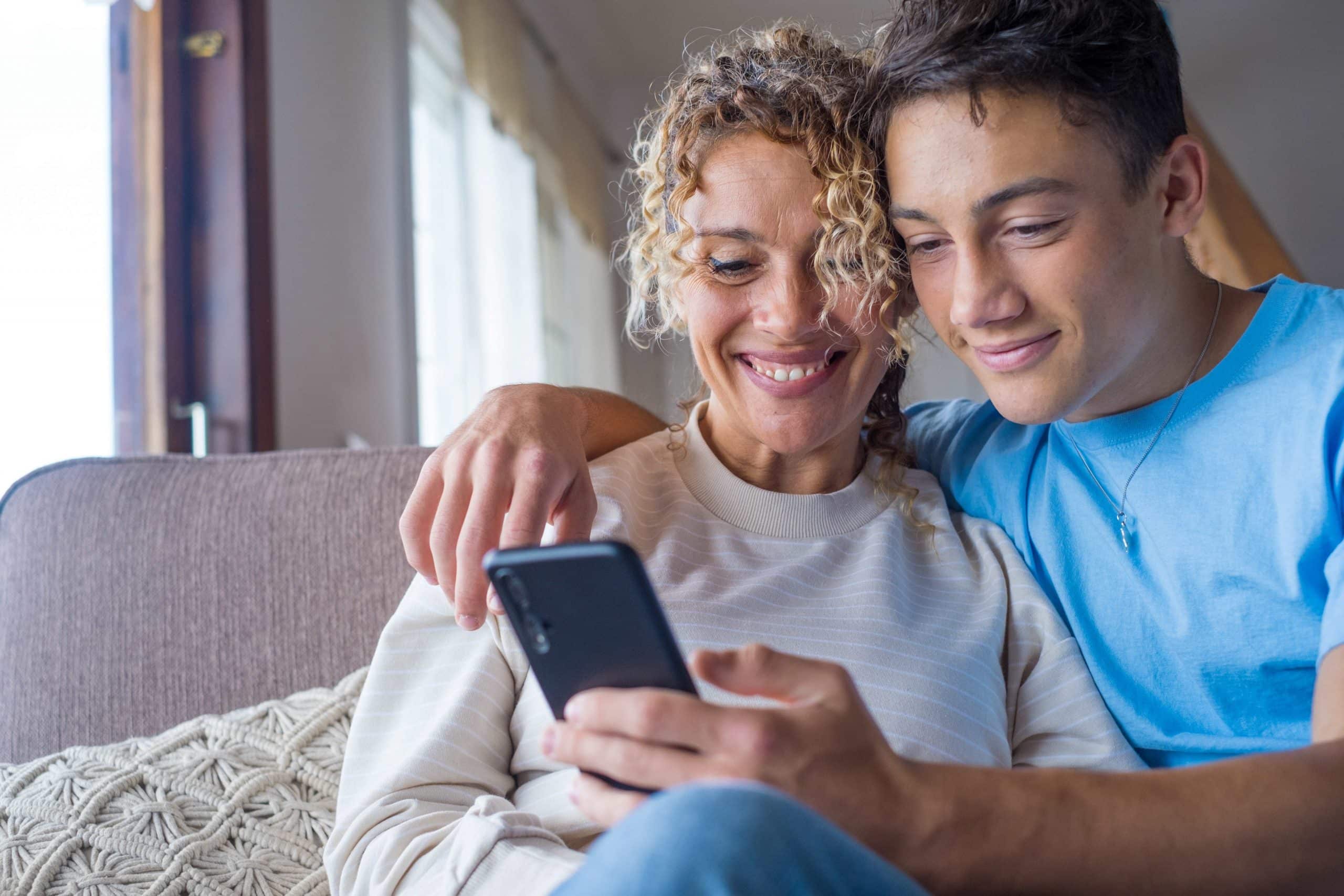 Puberzoon kijkt met moeder op mobiele telefoon